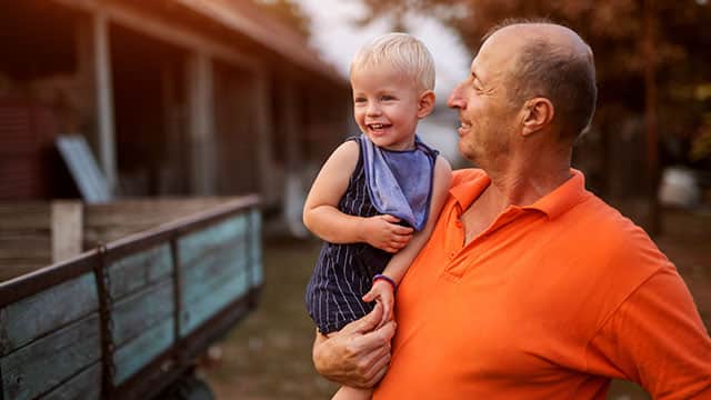 סבא מחזיק בנכדו ומביט בו.