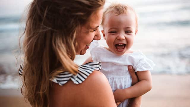 אימא מחזיקה תינוקת בחוף הים