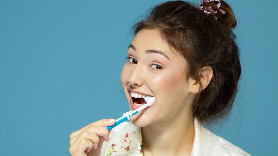 אישה מצחצחת שיניים כדי להראות איך למנוע ריח רע מהפה