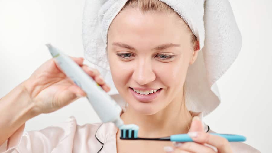 אישה מורחת משחת שיניים ללא גלוטן על מברשת שיניים
