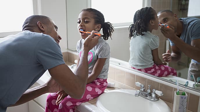 משפחה מצחצחת שיניים יחד להדגים איך לצחצח שיניים נכון